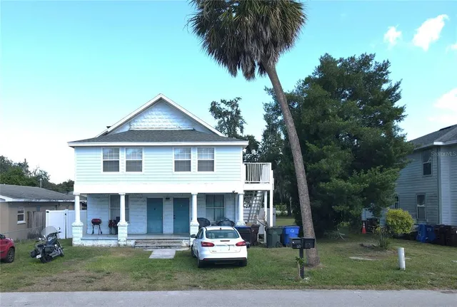 a front view of a house with a garden and trees
