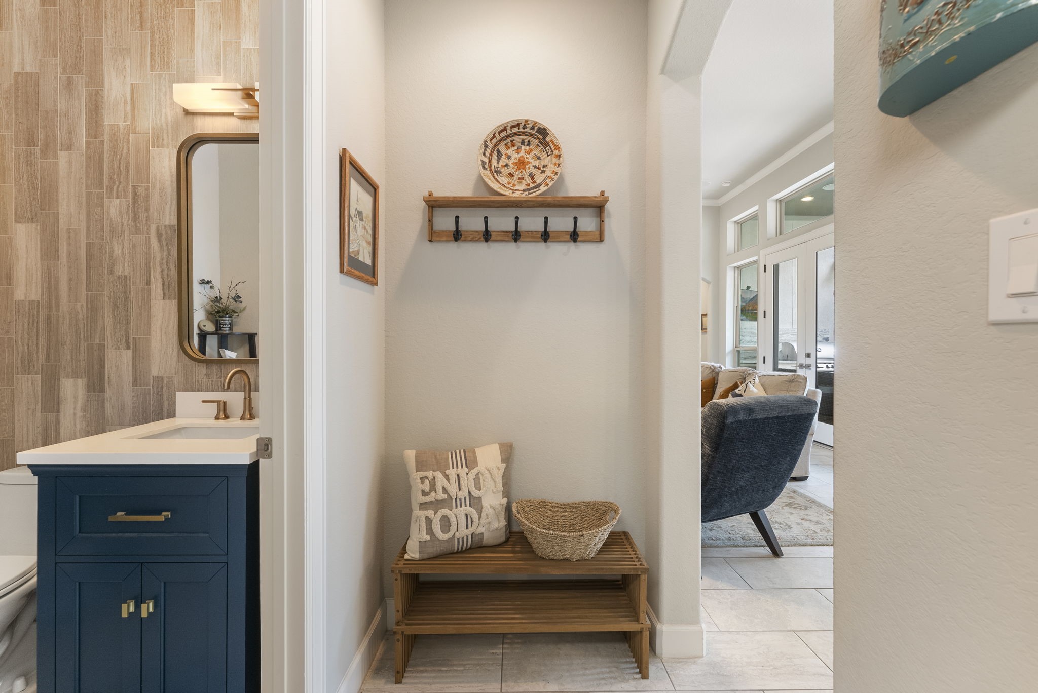 25607 Muirfield Bend Court Spring, TX 77389 - Photo 19 of 30 Conveniently located off the garage entry, this thoughtfully designed drop zone features a built-in bench, coat hooks, and dedicated storage space to keep daily essentials organized. Adjacent powder bath showcases stylish designer finishes, creating a functional and welcoming transition between the home, laundry room, and living spaces.