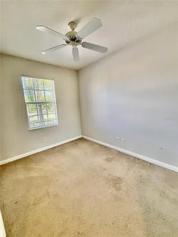 an empty room with windows and fan