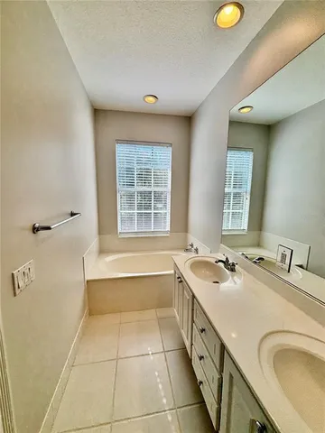 a spacious bathroom with a tub sink and mirror