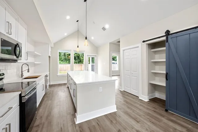 a large kitchen with granite countertop a large counter top space a sink stainless steel appliances and cabinets