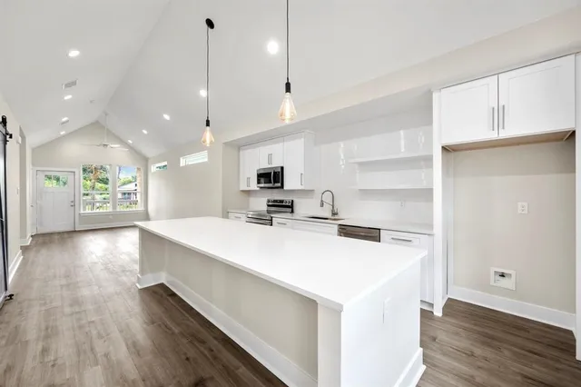 a large white kitchen with a large counter top space a sink and appliances