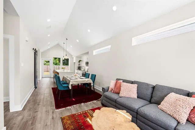 a living room with furniture kitchen view and a wooden floor