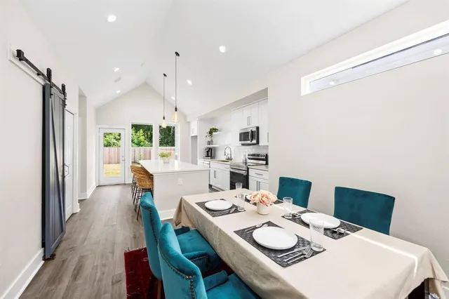 a large dining room with kitchen island stainless steel appliances furniture a large window and wooden floor
