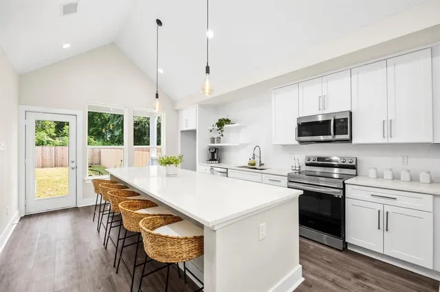 a kitchen with a stove a sink a microwave a dining table and chairs