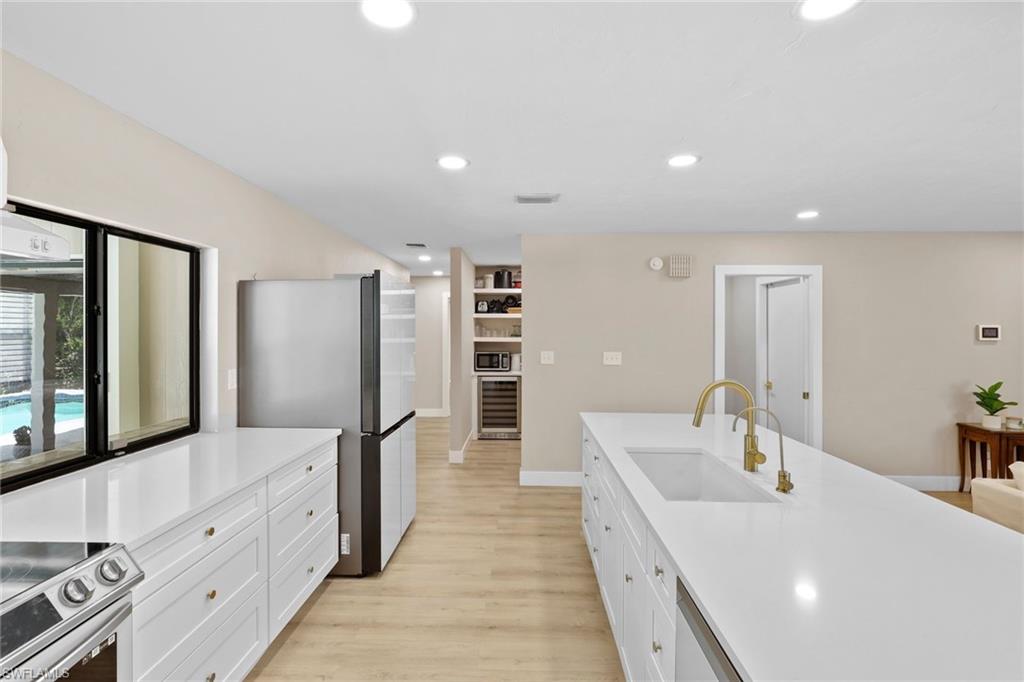 3221 68th Street Southwest Naples, FL 34105 - Photo 12 of 38 a large white kitchen with stainless steel appliances a large counter top a stove and a refrigerator