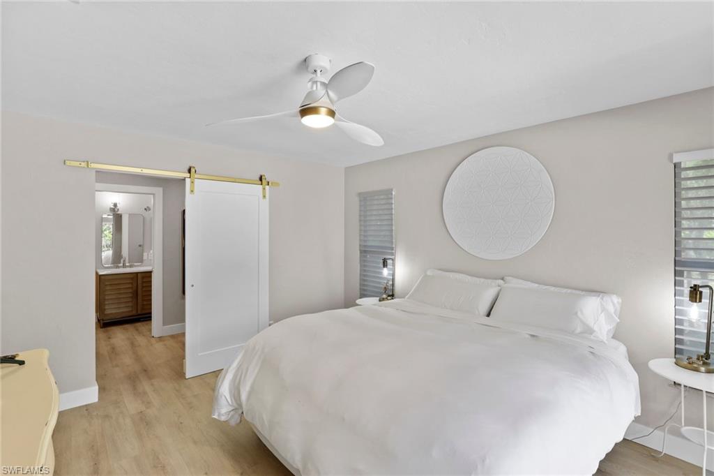 3221 68th Street Southwest Naples, FL 34105 - Photo 18 of 38 a bedroom with a bed and a chandelier