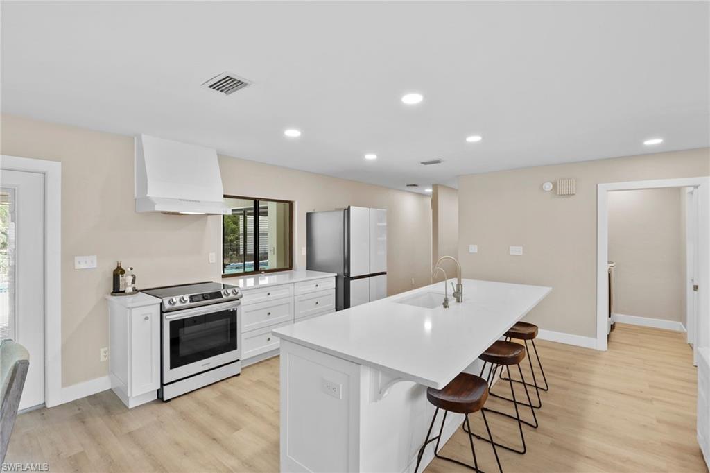 3221 68th Street Southwest Naples, FL 34105 - Photo 6 of 38 a kitchen with stainless steel appliances kitchen island granite countertop a stove a sink a refrigerator and a microwave