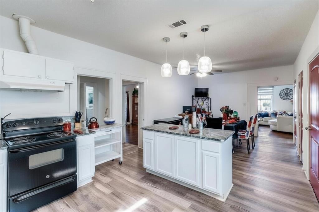2317 Anderson Street Dallas, TX 75215 - Photo 14 of 14 Kitchen featuring black / electric stove, white cabinetry, light stone countertops, and open floor plan