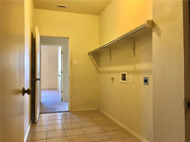a view of an empty room and chandelier fan