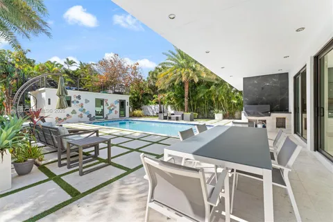 a view of a backyard with table and chairs under an umbrella with potted plants