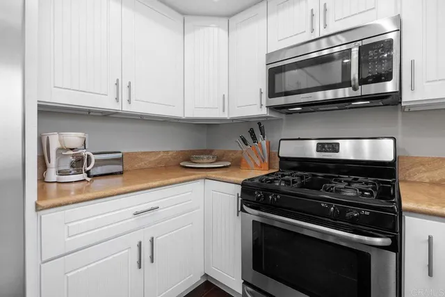 a kitchen with stainless steel appliances granite countertop grey cabinets a stove a sink and dishwasher