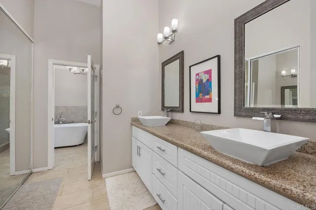 a en suite bathroom with a granite countertop tub a double vanity sink and a large mirror