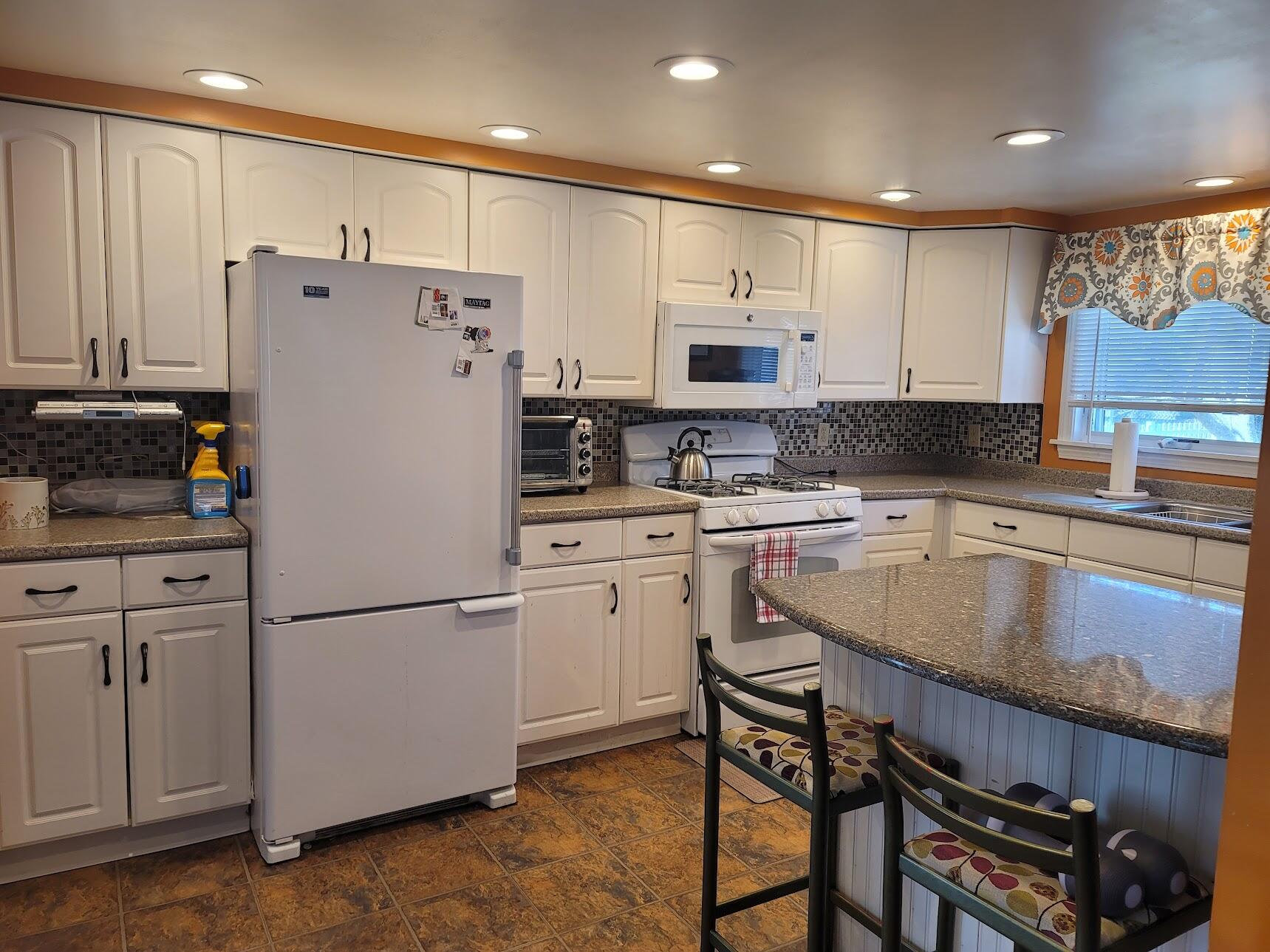 95 Spring Street Hyannis, MA 02601 - Photo 5 of 38 a kitchen with kitchen island granite countertop wooden cabinets and refrigerator