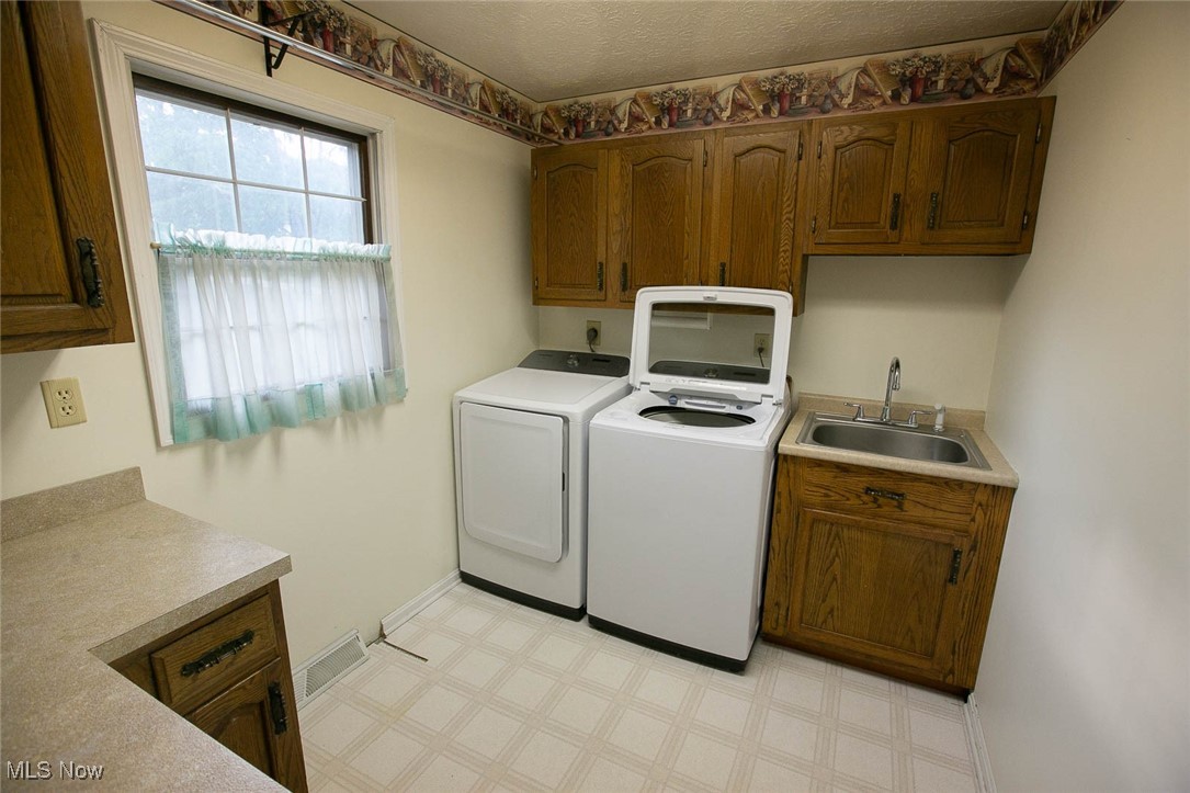 9046 River Styx Road Wadsworth, OH 44281 - Photo 11 of 30 Clothes washing area with sink, cabinets, light tile patterned floors, and washing machine and clothes dryer