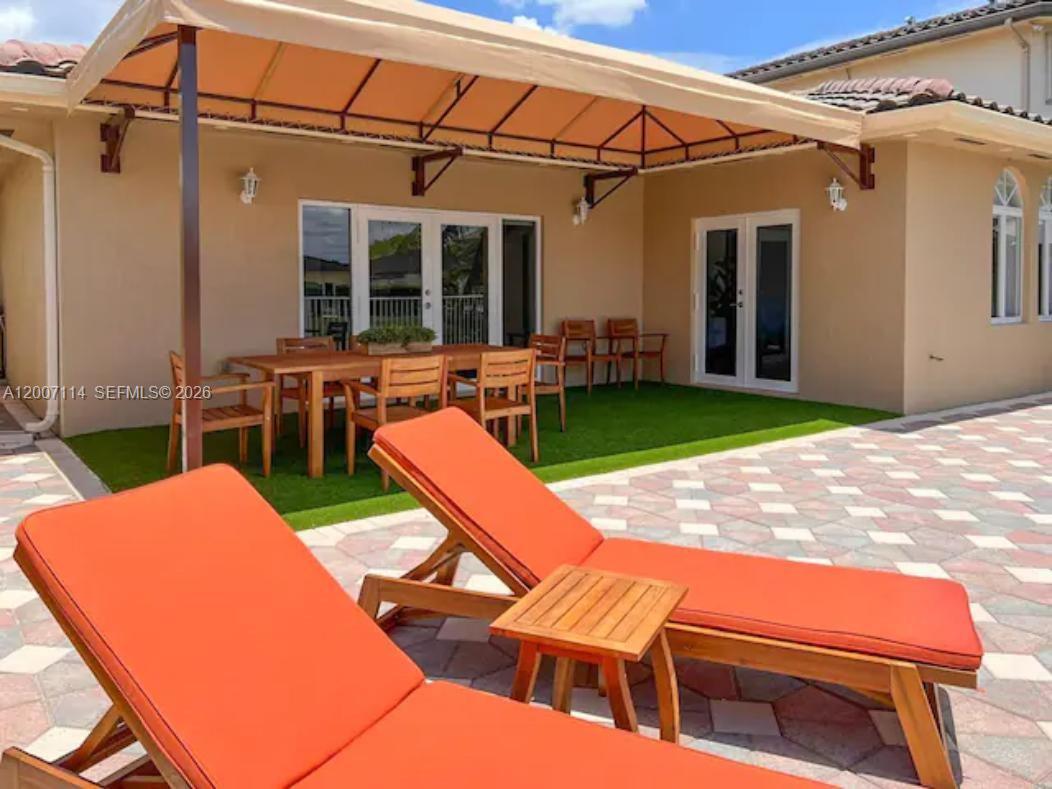 15566 Southwest 13th Terrace Miami, FL 33194 - Photo 23 of 27 a view of a patio with table and chairs with wooden floor and fence