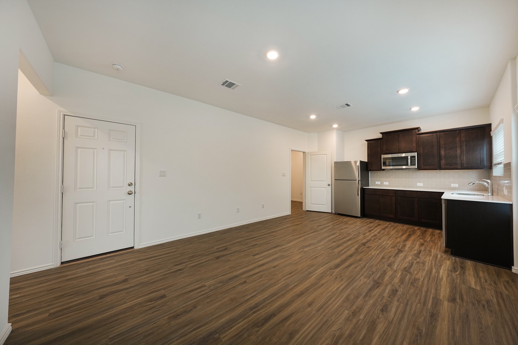 932 Mallow Road Leander, TX 78641 - Photo 7 of 34 A streamlined open-concept space features warm wood-tone flooring and a functional, compact kitchen.