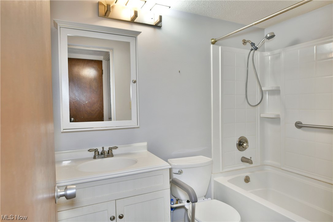 2980 North River Road Northeast, Unit E3 Warren, OH 44483 - Photo 18 of 27 Full bathroom featuring tub / shower combination, toilet, a textured ceiling, and vanity with extensive cabinet space