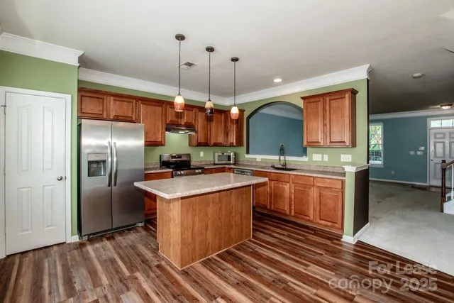 a kitchen with stainless steel appliances granite countertop a sink a stove and a refrigerator