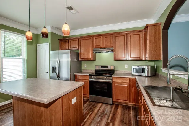 a kitchen with stainless steel appliances granite countertop a sink a stove and a refrigerator