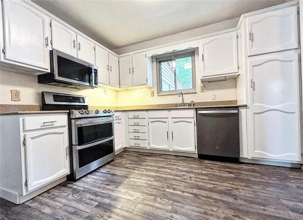 102 Crosslands Road Butler, PA 16002 - Photo 13 of 42 a kitchen with stainless steel appliances granite countertop a stove top oven a sink dishwasher and white cabinets with wooden floor