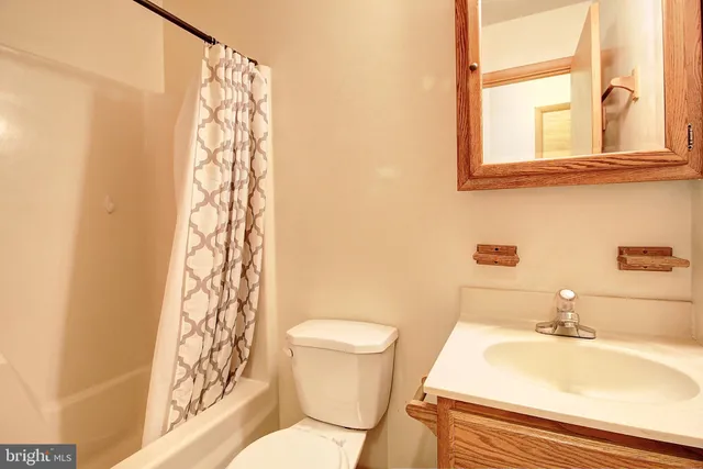 an empty room with wooden floor and windows with curtains