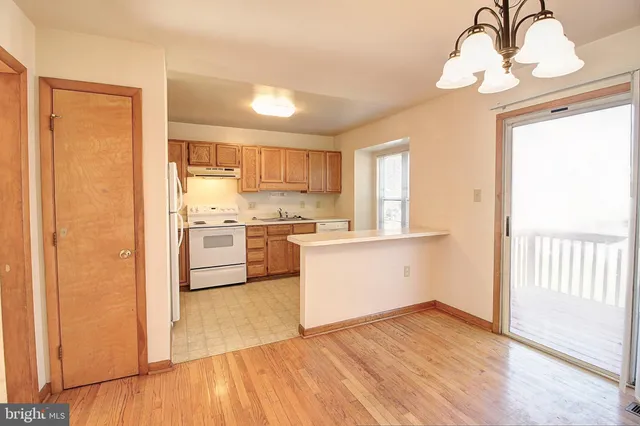 a kitchen with granite countertop a refrigerator a sink dishwasher a stove and white cabinets with wooden floor