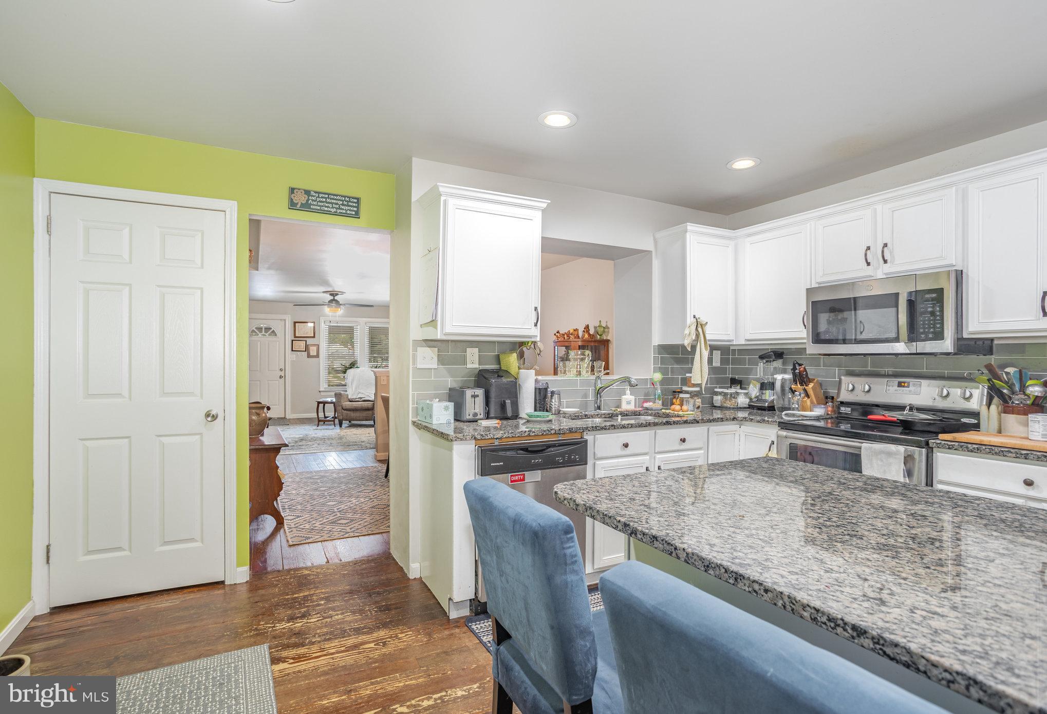 77 Petersburg Road Lancaster, PA 17601 - Photo 11 of 28 a kitchen with stainless steel appliances granite countertop a stove top oven a sink dishwasher a dining table and chairs with wooden floor