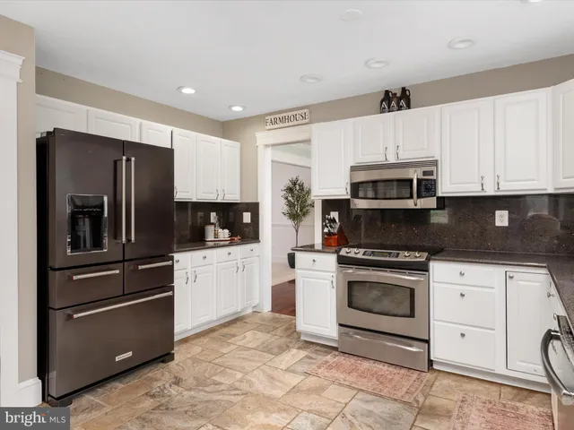 a kitchen with granite countertop white cabinets stainless steel appliances and a sink