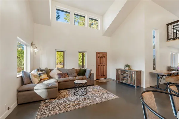 a living room with furniture a rug kitchen view and a large window