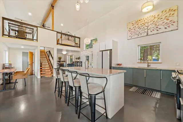 a living room with couches chairs and kitchen view with wooden floor