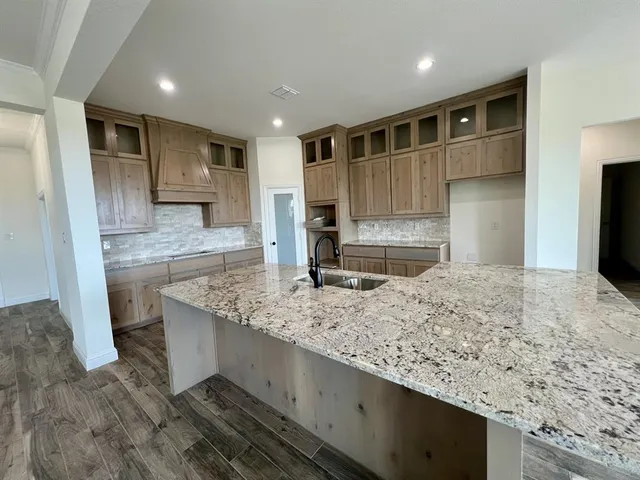 a large kitchen with kitchen island granite countertop a large counter top and wooden cabinets
