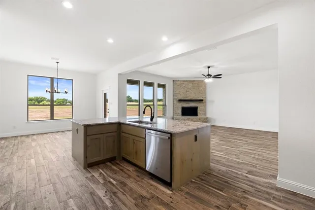 a large kitchen with stainless steel appliances granite countertop a stove and a wooden floors
