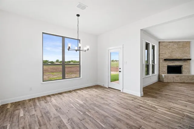 a view of an empty room with window and wooden floor