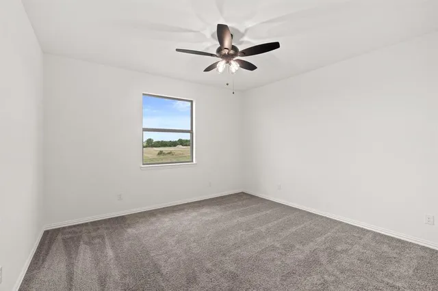 an empty room with a window and a fan