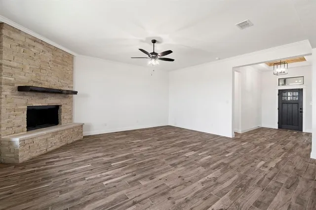 a view of a livingroom with a fireplace a ceiling fan and wooden floor