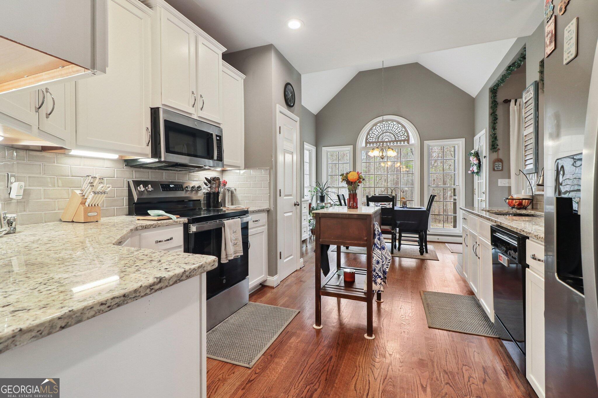 3792 Falls Trail Winston, GA 30187 - Photo 14 of 24 a kitchen with stainless steel appliances granite countertop a stove top oven a sink a dining table and chairs with wooden floor