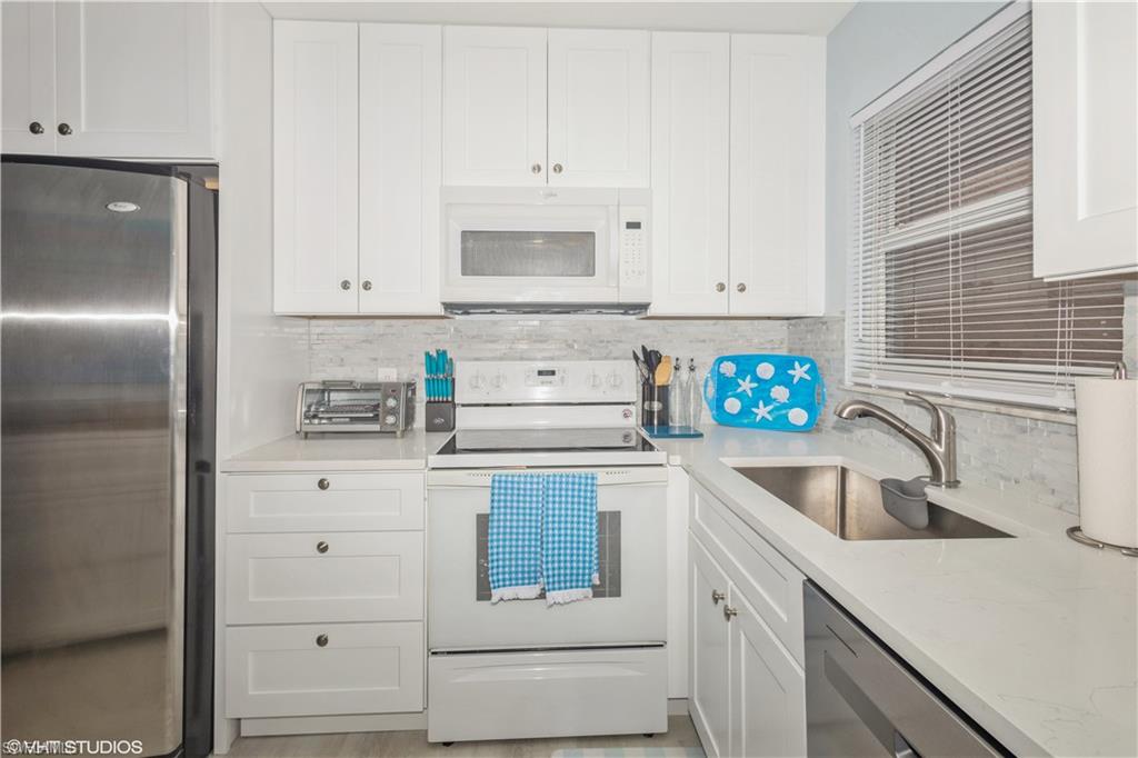 190 Turtle Lake Court, Unit 311 Naples, FL 34105 - Photo 16 of 47 a kitchen with granite countertop white cabinets and stainless steel appliances