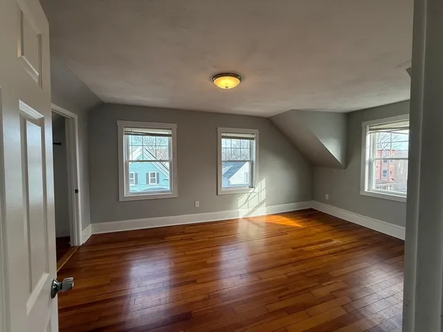a view of an empty room with window and wooden floor
