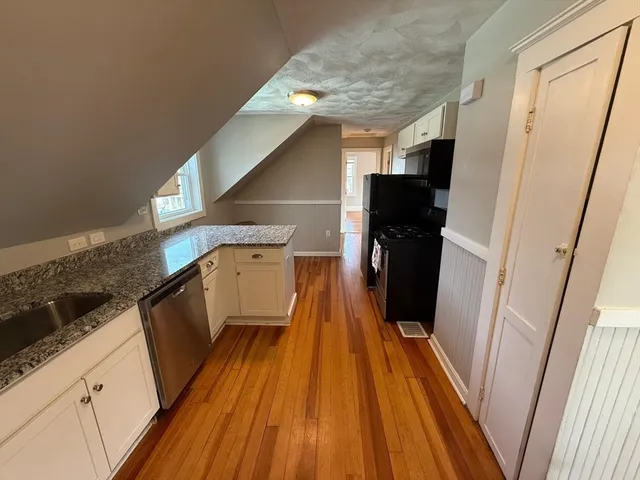 a view of entryway and kitchen with wooden floor