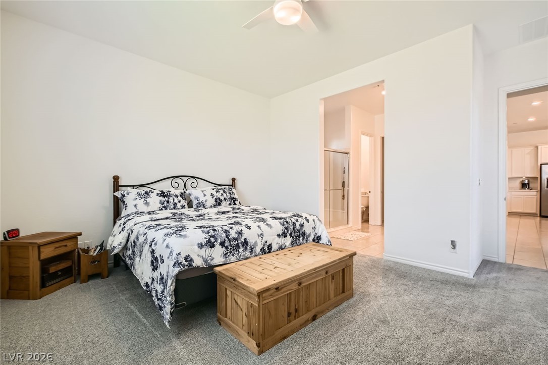 498 Pebble Run Avenue Henderson, NV 89011 - Photo 11 of 47 This primary bedroom features plush carpeting and offers a private en suite bathroom access.