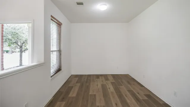 a view of empty room with wooden floor and fan