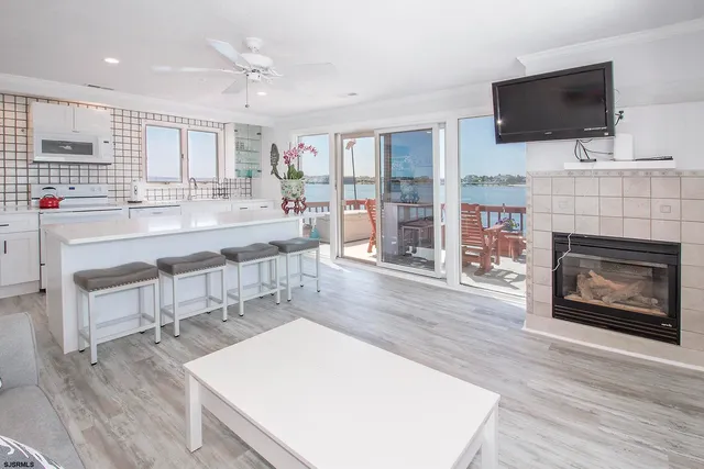 a large living room with stainless steel appliances furniture a fireplace and a flat screen tv