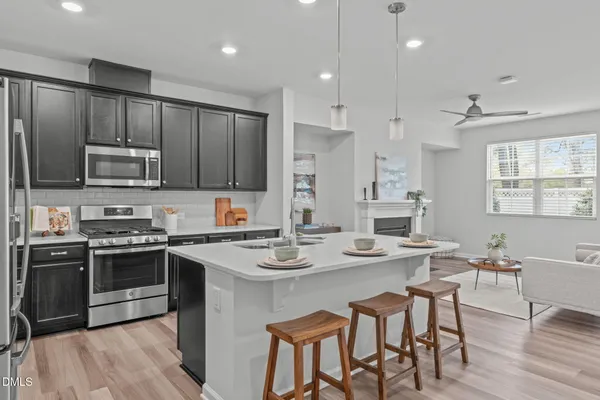 a kitchen with refrigerator a stove a sink and chairs