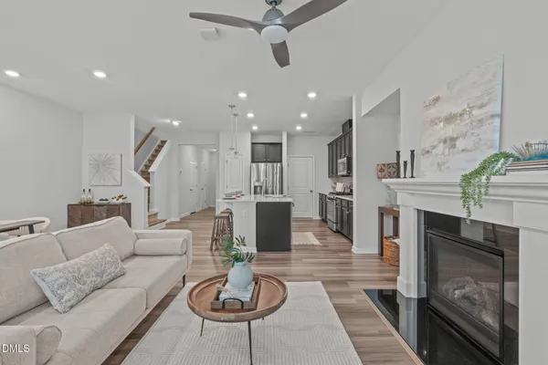 a living room with furniture kitchen view and a wooden floor
