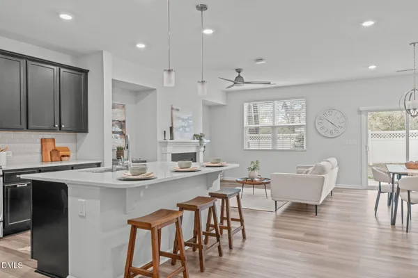 a large kitchen with kitchen island a dining table chairs and white cabinets