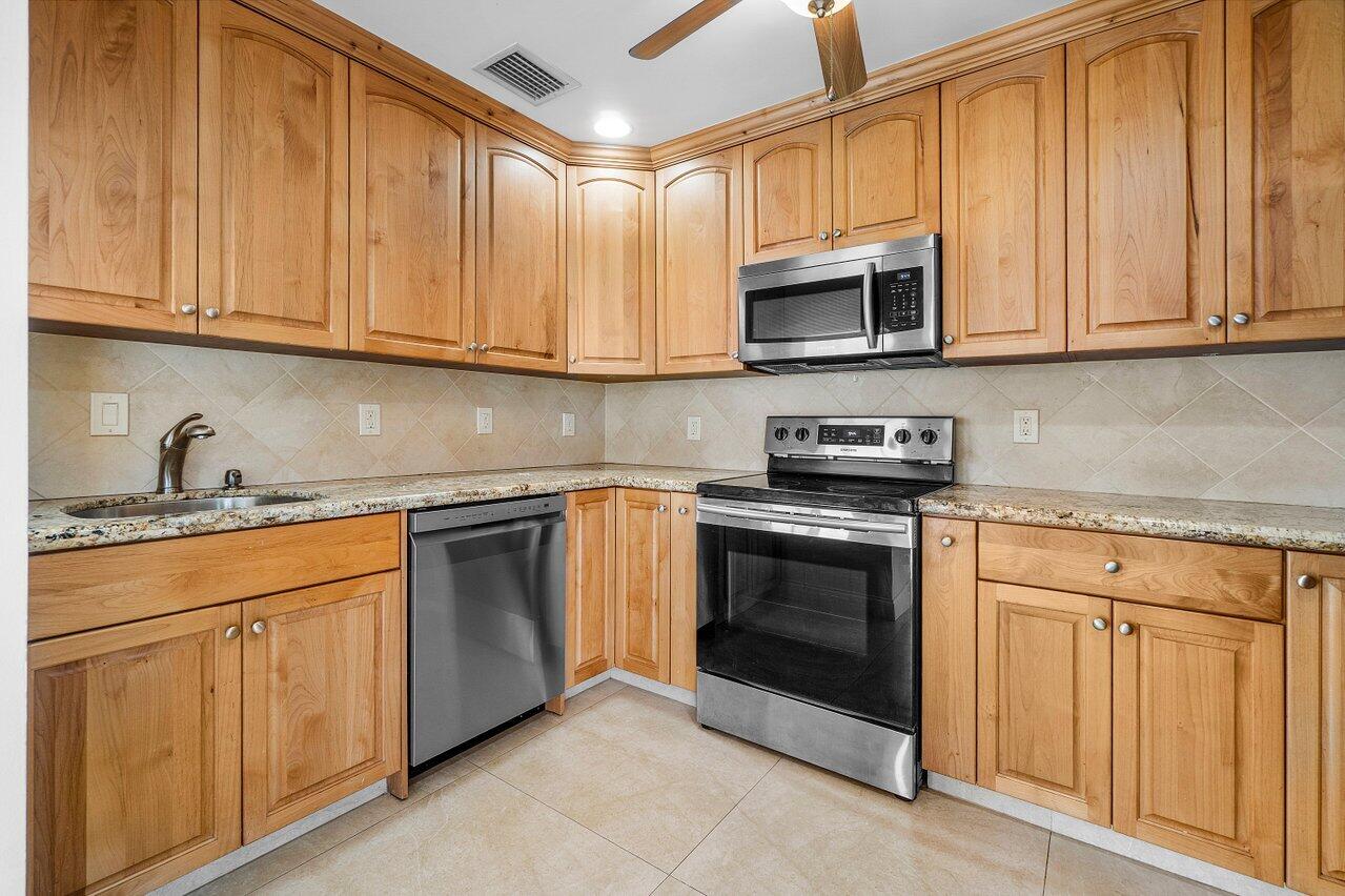 362 Yorktowne Circle Atlantis, FL 33462 - Photo 5 of 41 a kitchen with stainless steel appliances granite countertop white cabinets a sink and dishwasher