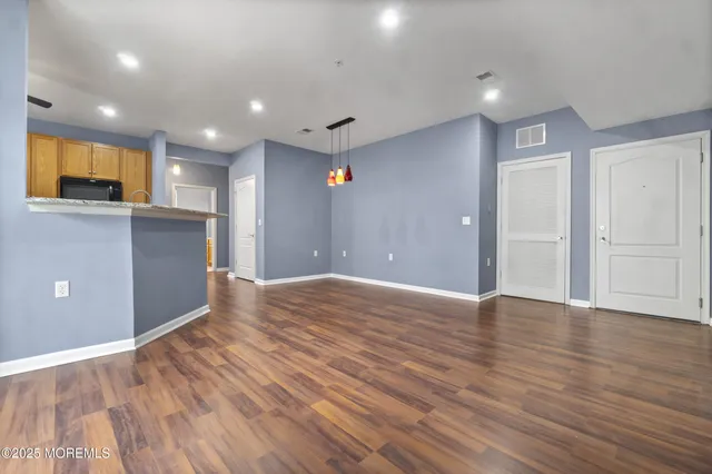 a view of empty room with wooden floor and kitchen view