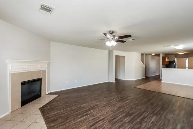 a view of an empty room with wooden floor and a fireplace