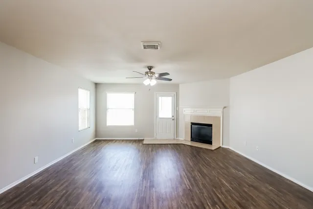 an empty room with wooden floor fireplace and windows